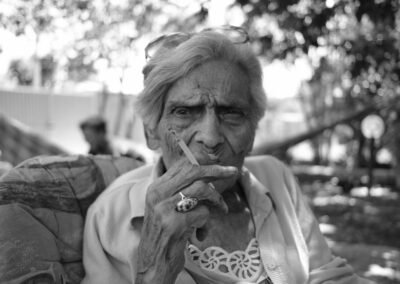 Black and white portrait of an elderly woman smoking a cigarette outdoors