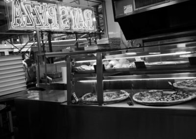 Black and white photo of pizzas in the display case at Ray's Pizza
