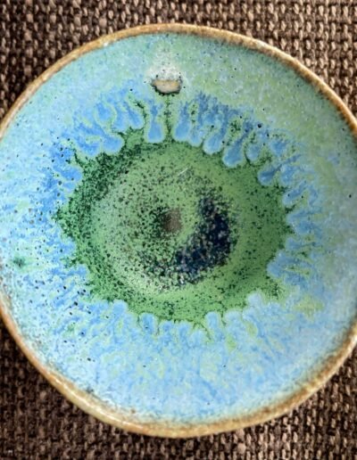 Small ceramic bowl with speckled turquoise and green glaze radiating from its center