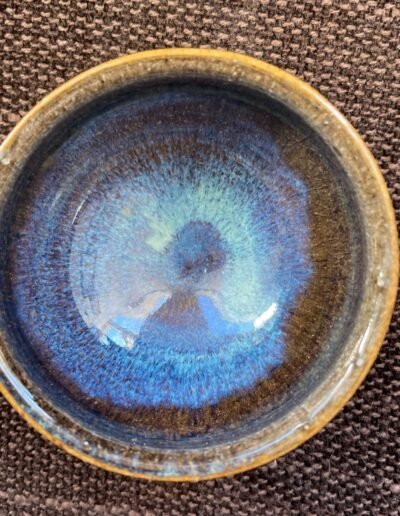 Handmade ceramic bowl with deep blue glaze streaking toward a luminous center