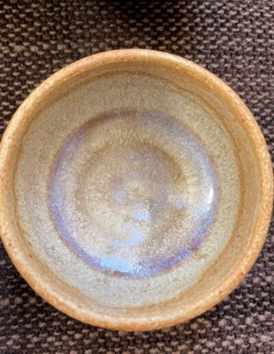 Earth-toned ceramic bowl with a pearly lavender sheen inside