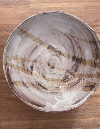 Handmade ceramic bowl with brown brushstroke swirls on cream glaze