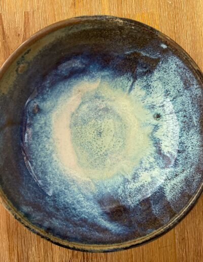 Blue glazed ceramic bowl with a cloudy white center on a wooden table