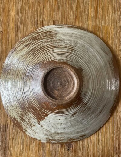 Underside of a ridged ceramic plate in rust and white tones