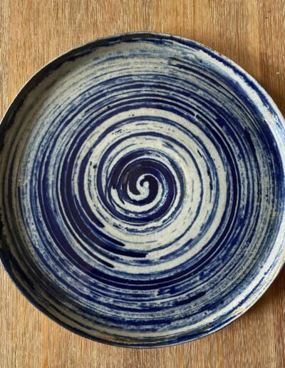 Ceramic platter with a hypnotic indigo spiral over cream glaze
