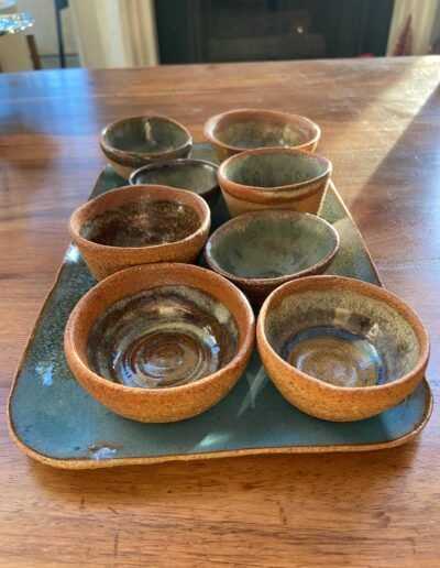 Set of small rust-orange glazed bowls arranged on a turquoise tray